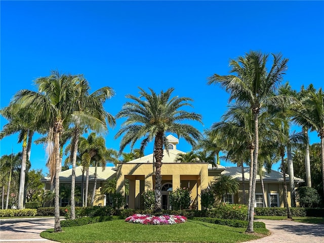 view of front of property featuring stucco siding, decorative driveway, and a front yard