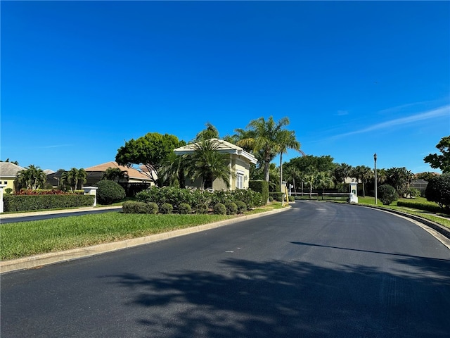 view of street with street lights, curbs, a gated entry, and a residential view