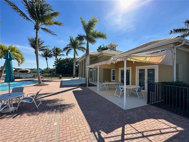 view of patio / terrace with french doors, fence, and a community pool