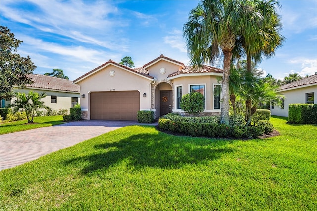 mediterranean / spanish house featuring a garage and a front yard