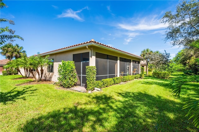 rear view of property featuring a sunroom and a yard