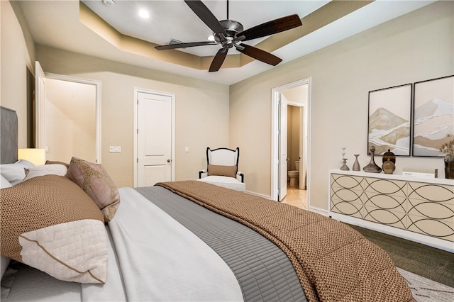 bedroom featuring ensuite bathroom, ceiling fan, and a tray ceiling