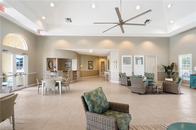 living room featuring a towering ceiling, ceiling fan, and plenty of natural light