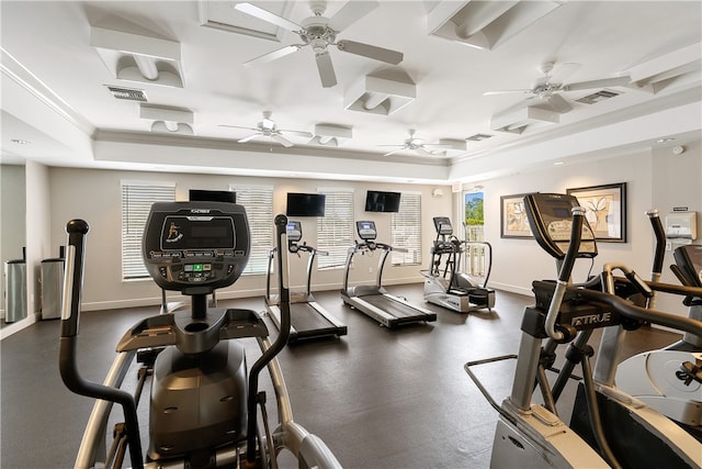 exercise room with a wealth of natural light, ceiling fan, a raised ceiling, and crown molding