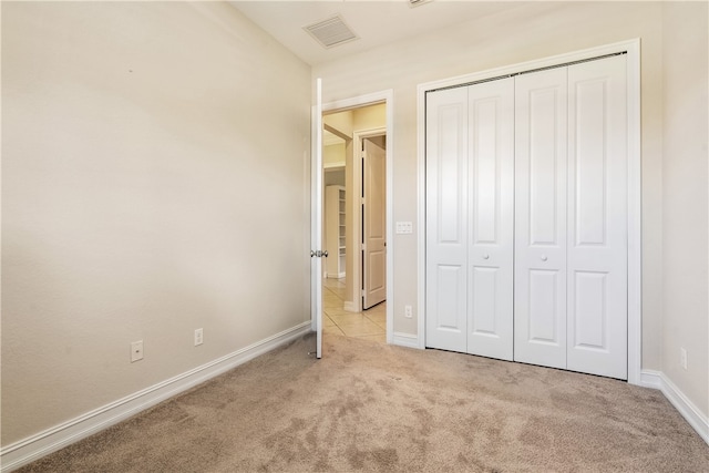 unfurnished bedroom featuring light carpet and a closet