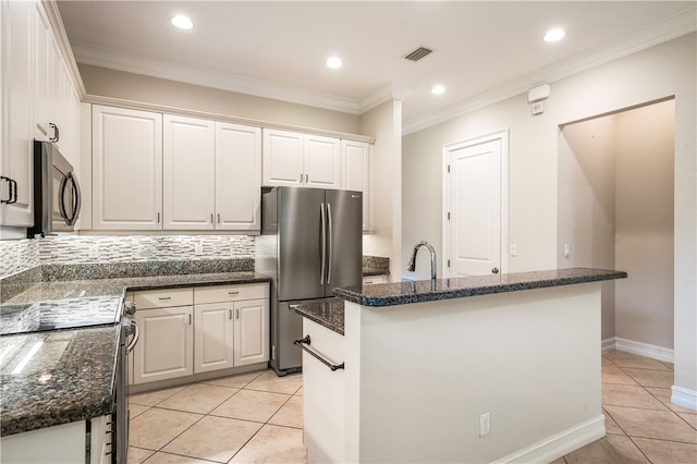 kitchen with tasteful backsplash, white cabinetry, appliances with stainless steel finishes, and a kitchen island with sink