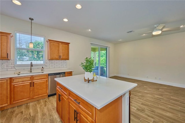 kitchen with sink, backsplash, a center island, light hardwood / wood-style floors, and stainless steel dishwasher