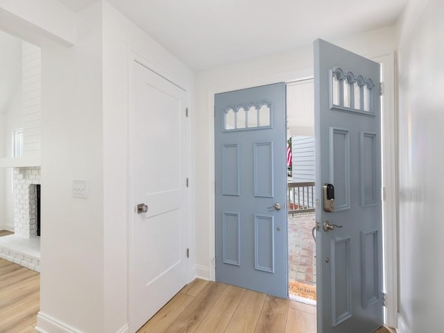 entrance foyer featuring a brick fireplace and wood-type flooring