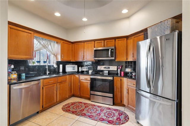 kitchen with sink, light tile patterned floors, appliances with stainless steel finishes, dark stone counters, and decorative backsplash