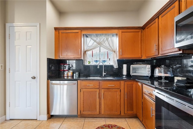 kitchen featuring light tile patterned flooring, sink, decorative backsplash, dark stone counters, and stainless steel appliances