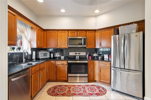 kitchen featuring sink, dark stone countertops, stainless steel appliances, tasteful backsplash, and light tile patterned flooring