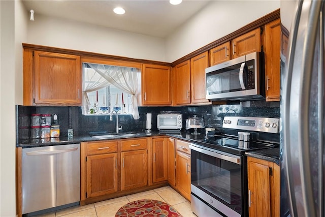 kitchen featuring light tile patterned flooring, appliances with stainless steel finishes, tasteful backsplash, sink, and dark stone countertops