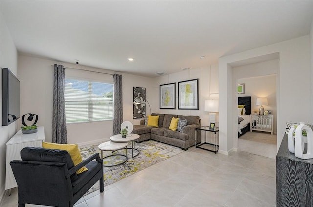 living area featuring light tile patterned floors, visible vents, and baseboards