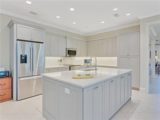 kitchen featuring sink, light tile patterned floors, a kitchen island with sink, stainless steel appliances, and ornamental molding