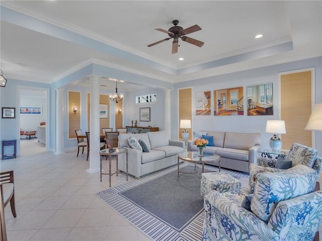 tiled living room with decorative columns, a raised ceiling, ornamental molding, and ceiling fan with notable chandelier