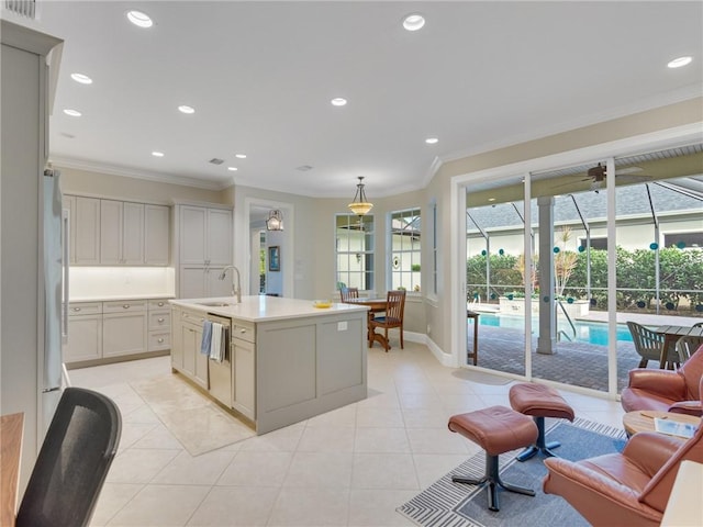 kitchen with crown molding, sink, an island with sink, and hanging light fixtures