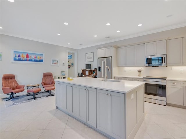 kitchen with sink, crown molding, light tile patterned floors, stainless steel appliances, and a kitchen island with sink