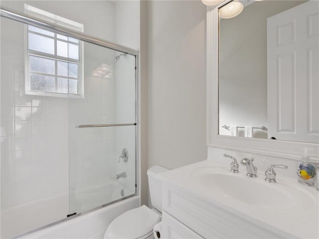 full bathroom featuring vanity, enclosed tub / shower combo, and toilet