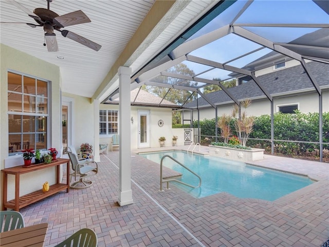 view of swimming pool with glass enclosure, ceiling fan, and a patio area