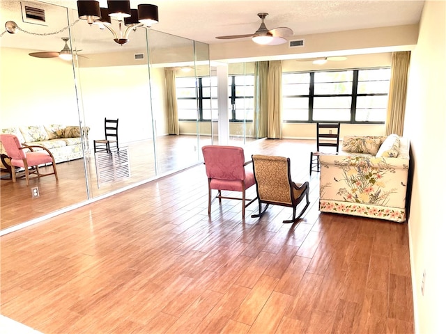 living area featuring a wealth of natural light, a textured ceiling, hardwood / wood-style flooring, and ceiling fan