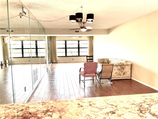 living area with hardwood / wood-style flooring, a textured ceiling, and a notable chandelier