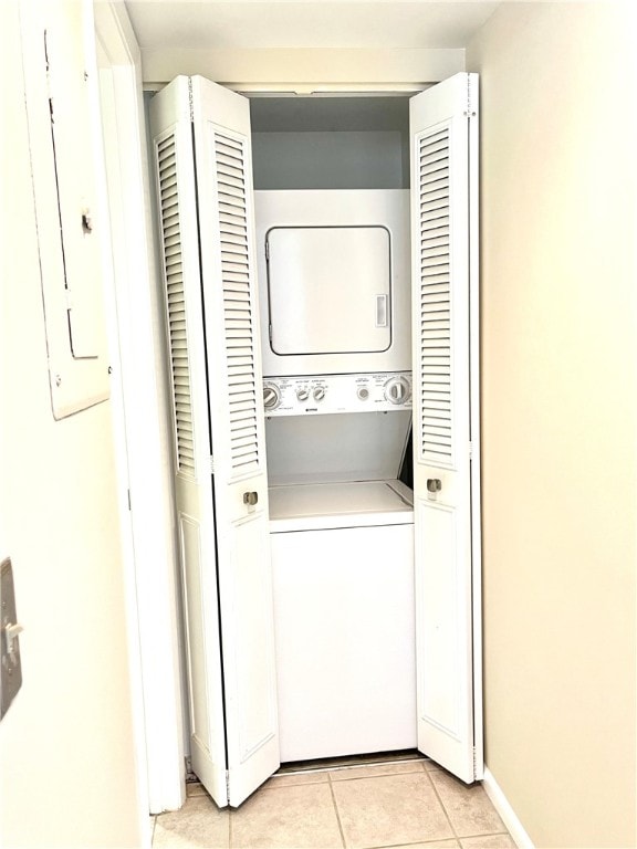 laundry area with stacked washing maching and dryer, electric panel, and light tile patterned flooring