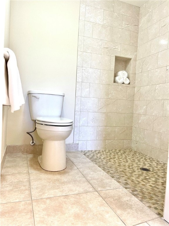 bathroom with tile patterned flooring, toilet, and tiled shower