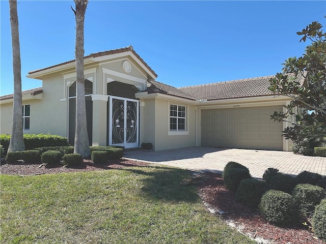 view of front of house featuring an attached garage, a tile roof, decorative driveway, and stucco siding