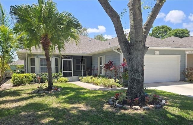 view of front of house featuring a sunroom, a garage, a shingled roof, and a front yard