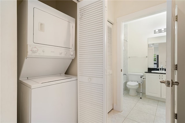 laundry area with sink, stacked washer / drying machine, and light tile patterned flooring