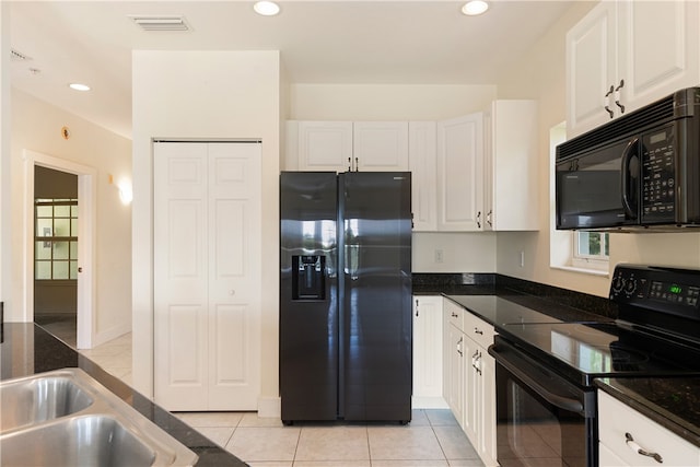 kitchen featuring white cabinets, light tile patterned flooring, dark stone countertops, and black appliances