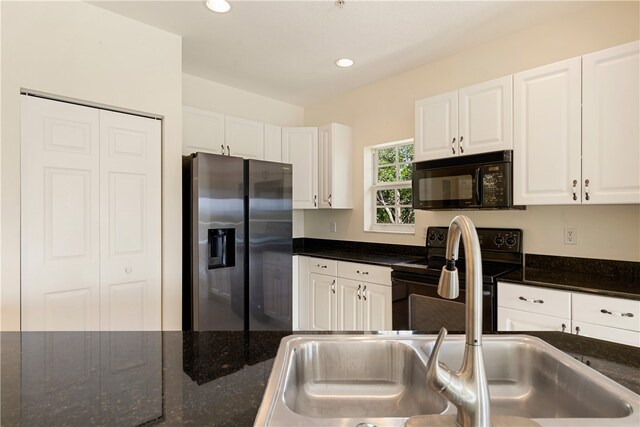 kitchen with black appliances, dark stone counters, sink, and white cabinets