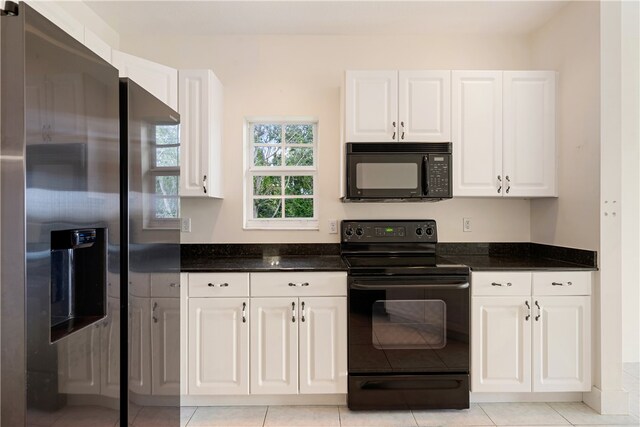 kitchen featuring black appliances, dark stone countertops, light tile patterned floors, and white cabinets