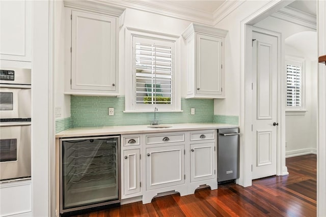121 Palm Island Ln, Vero Beach, FL 32963 - bar area featuring wine cooler, a sink, stainless steel double oven, dark wood-style floors, and crown molding