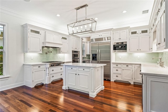 121 Palm Island Ln, Vero Beach, FL 32963 - kitchen featuring appliances with stainless steel finishes, a sink, custom exhaust hood, light countertops, and ornamental molding