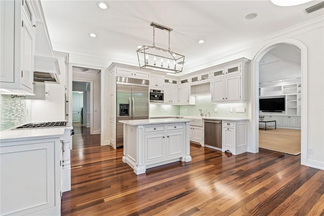 121 Palm Island Ln, Vero Beach, FL 32963 - kitchen featuring stainless steel appliances, tasteful backsplash, light countertops, glass insert cabinets, and ornamental molding