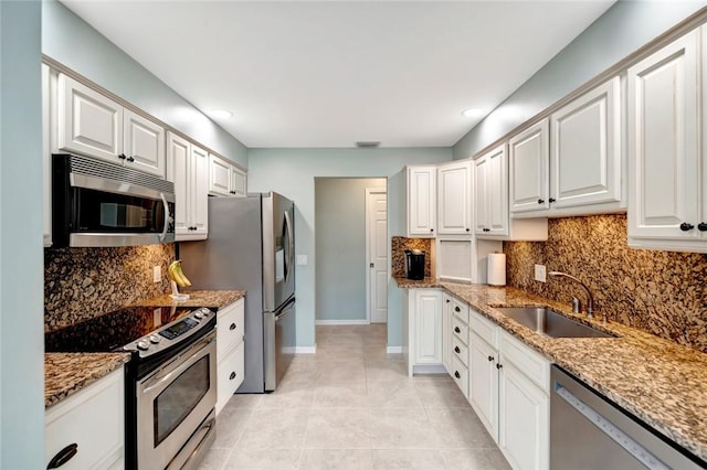 kitchen with light stone countertops, white cabinetry, sink, and stainless steel appliances