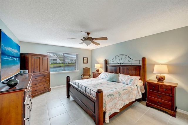 bedroom featuring ceiling fan, light tile patterned floors, and a textured ceiling