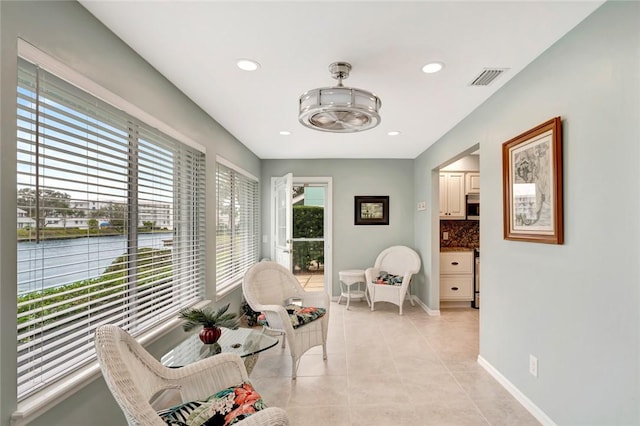 sitting room with a water view and light tile patterned floors