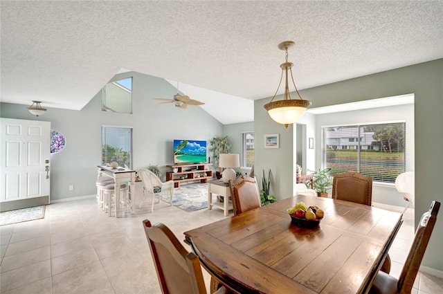 tiled dining space featuring a textured ceiling, ceiling fan, and lofted ceiling