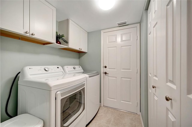 washroom featuring cabinets, light tile patterned floors, and washing machine and clothes dryer