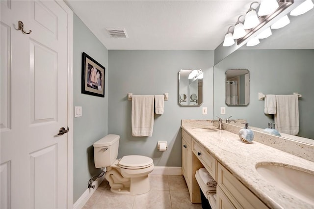 bathroom with toilet, vanity, and tile patterned floors