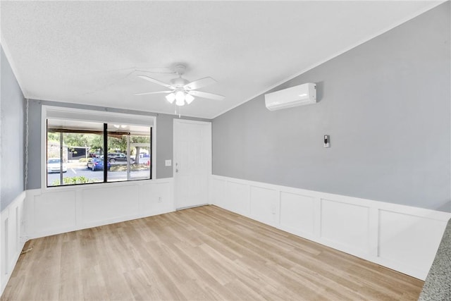 unfurnished room with a decorative wall, an AC wall unit, ceiling fan, and a wainscoted wall