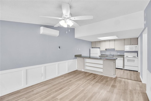 kitchen featuring a peninsula, a decorative wall, white appliances, an AC wall unit, and a sink