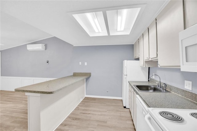 kitchen featuring white cabinets, a sink, white appliances, light wood-style flooring, and a peninsula