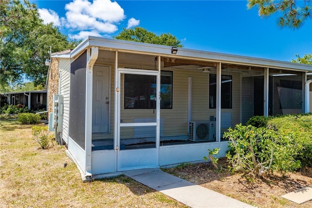 view of front facade with a sunroom, ac unit, and a front yard
