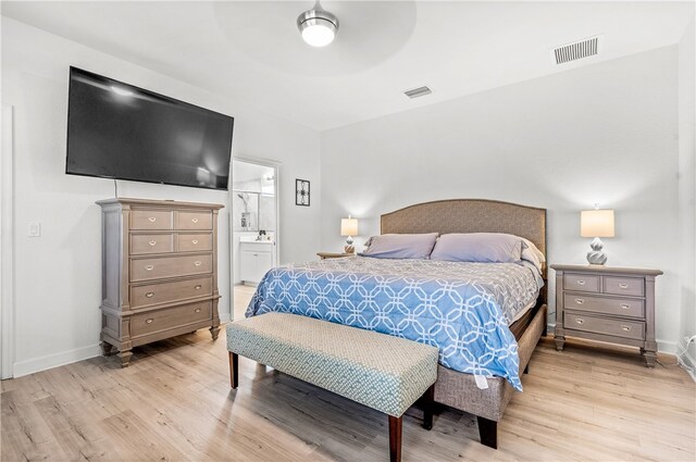 bedroom with ceiling fan, ensuite bath, and light wood-type flooring