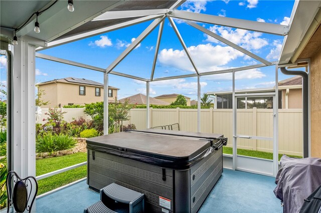 view of patio / terrace featuring glass enclosure and a hot tub