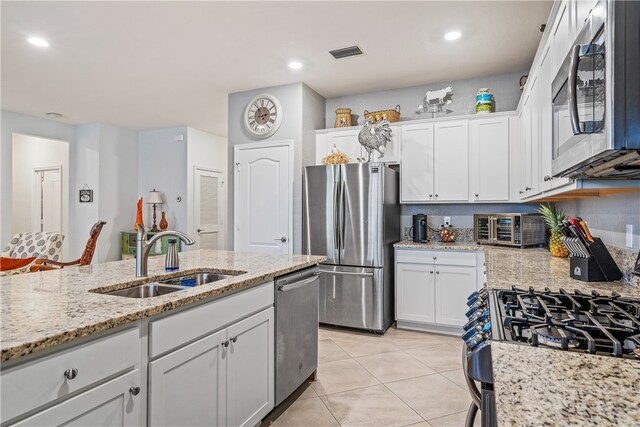 kitchen featuring stainless steel appliances, white cabinets, light tile patterned floors, sink, and light stone countertops