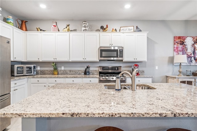 kitchen featuring stainless steel appliances, a kitchen bar, white cabinets, and sink